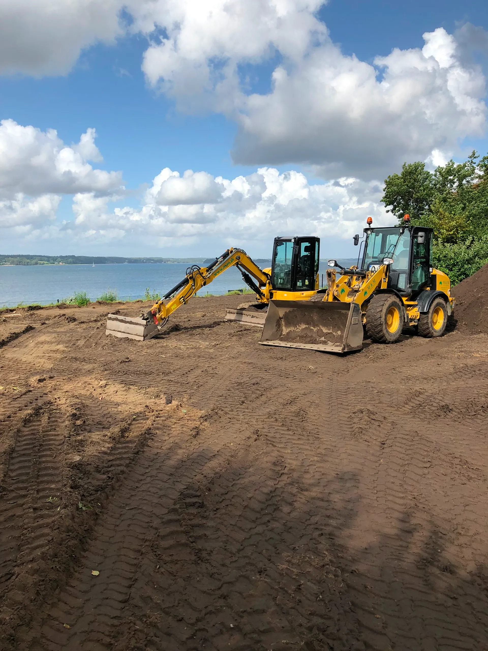 Bagger und Radlader stehen auf einer Erdfläche